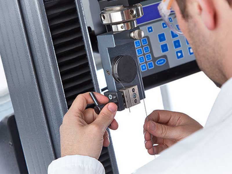 man adjusting settings on bed spring making machine - Sussex Beds